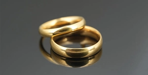 Macro shot of two polished gold titanium wedding rings with a mirror reflection on black