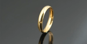 Close-up of a minimalist gold-plated titanium ring with a high-polished mirror finish