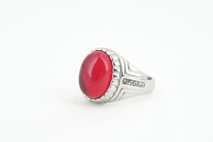 Détail d'une bague pour homme avec une grande pierre rouge ovale et un anneau argenté