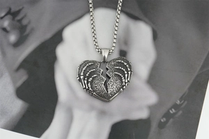 Détail du pendentif coeur vintage avec griffe squelettique et chaîne en métal
