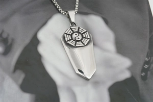 Macro detail of retro stainless steel Yin Yang Bagua coffin pendant on a box chain