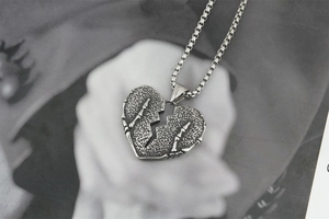 Détail d'un pendentif coeur gothique avec mains de squelette en argent vieilli
