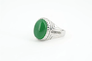 Détail macro d'une bague avec pierre précieuse verte ovale et monture argentée