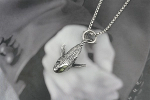Détail macro du pendentif baleine rétro argenté avec écailles et œil en gemme verte