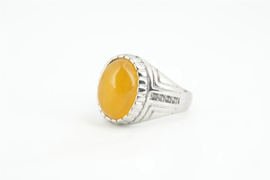 Gros plan d'une bague argentée avec une grande pierre jaune ovale et des gravures latérales