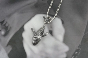 Gros plan du pendentif baleine vintage avec détails texturés sur une chaîne box