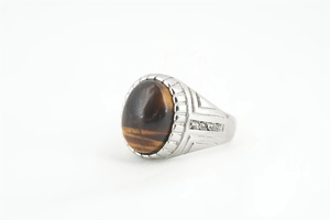 Détail de bague pour homme avec pierre oeil de tigre, anneau argenté et cristaux latéraux