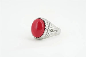 Gros plan d'une bague en argent avec pierre rouge ovale et pavé de strass sur l'anneau