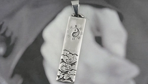 Detailed macro view of rectangular titanium steel pendant with Tai Chi and cloud patterns