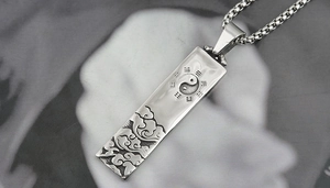 Macro detail of stainless steel pendant with Tai Chi Bagua and auspicious cloud patterns
