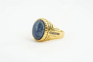 Vue macro d'une bague vintage dorée avec une pierre ovale bleue et des accents de zircon