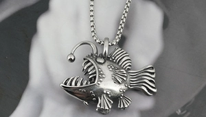 Macro view of a punk style anglerfish pendant with vintage box chain in titanium steel