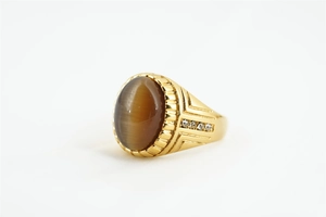 Détail de la bague dorée ornée d'une pierre œil-de-chat brune et petits diamants