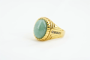 Détail d'une bague dorée avec pierre précieuse verte ovale et petits diamants
