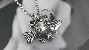 Macro detail of silver finish anglerfish pendant with sharp teeth and box chain