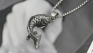 Gros plan sur un pendentif carpe koï en argent avec chaîne et texture vintage mate
