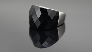 Macro shot of oversized faceted black obsidian stone ring with polished silver band
