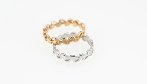 Macro shot of gold and silver olive leaf rings with elegant cutout patterns on white background