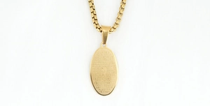 Detailed close-up of golden titanium steel oval pendant with engraved religious scriptures
