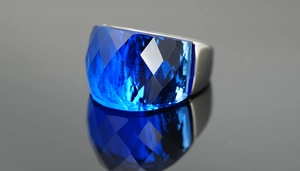 Macro shot of large faceted blue gemstone ring with polished silver band and reflection