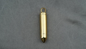 Goldener Patronenanhänger mit Schraubverschluss für Parfüm oder Asche auf grauem Stoff