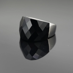 Polished silver ring with a large faceted black gemstone on a reflective dark background
