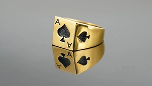 Macro side view of golden Ace of Spades signet ring with black enamel on mirror background