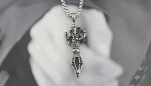 Detail of vintage titanium steel Ganesha and Vajra pendant with aged finish texture
