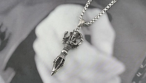 Macro detail of antique silver Ganesha and Vajra pendant with intricate engraved textures