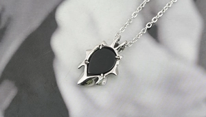 Macro shot of gothic teardrop black agate pendant with spiky silver-tone setting