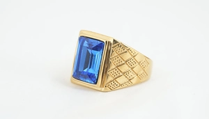 Detailansicht eines goldenen Titanrings mit großem blauem Edelstein und geprägter Textur am Band