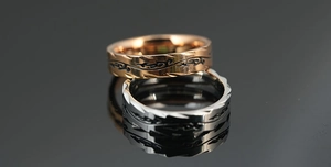 Macro view of titanium steel rings with black vine engraving and serrated edge design