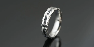 Macro shot of silver titanium ring featuring wave faceted edges and black dragon patterns