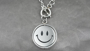 Detail of titanium steel necklace showing OT buckle and rotating smiley face pendant