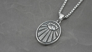 Macro view of titanium steel pendant featuring embossed All-Seeing Eye and box chain detail