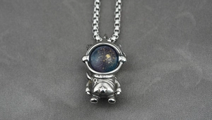 Macro shot of astronaut pendant with blue starry bead and vintage silver chain detail