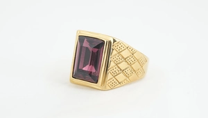 Detaillierte Nahaufnahme eines goldenen Titanrings mit lila Stein und strukturierter Ringschiene