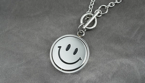 Detail of a rotating double-sided smiley face pendant with a stylish toggle clasp chain