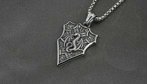 Macro view of vintage shield pendant with Viking dragon relief on a steel pearl chain
