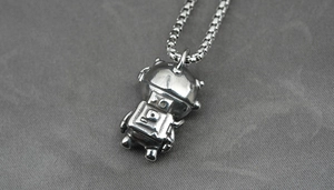 Close-up of retro silver astronaut pendant necklace on a textured grey background