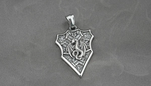 Detail macro view of a vintage titanium steel shield pendant with a dragon relief