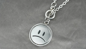 Detail of silver titanium steel sad face rotating pendant with chunky link toggle chain