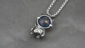 Macro shot of silver astronaut pendant with blue starry visor and box chain texture