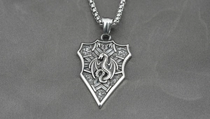 Detail of vintage shield pendant featuring an engraved dragon and antique finish steel