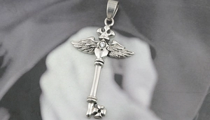 Détail macro du pendentif clé gothique en argent avec ailes, cœur, croix et couronne