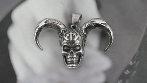 Detailed macro view of vintage silver goat skull pendant with gothic crown carvings