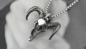 Detailed macro view of a punk style ram skull pendant with textured horns and silver chain