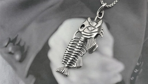 Detail showing vintage titanium steel fish skeleton pendant with rustic oxidation finish