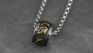 Makroaufnahme einer Titanstahlkette mit Retro-Drehperle und goldenen Sutra-Symbolen