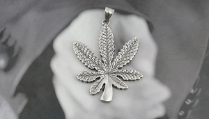 Macro view of vintage silver maple leaf pendant with detailed texture on steel chain